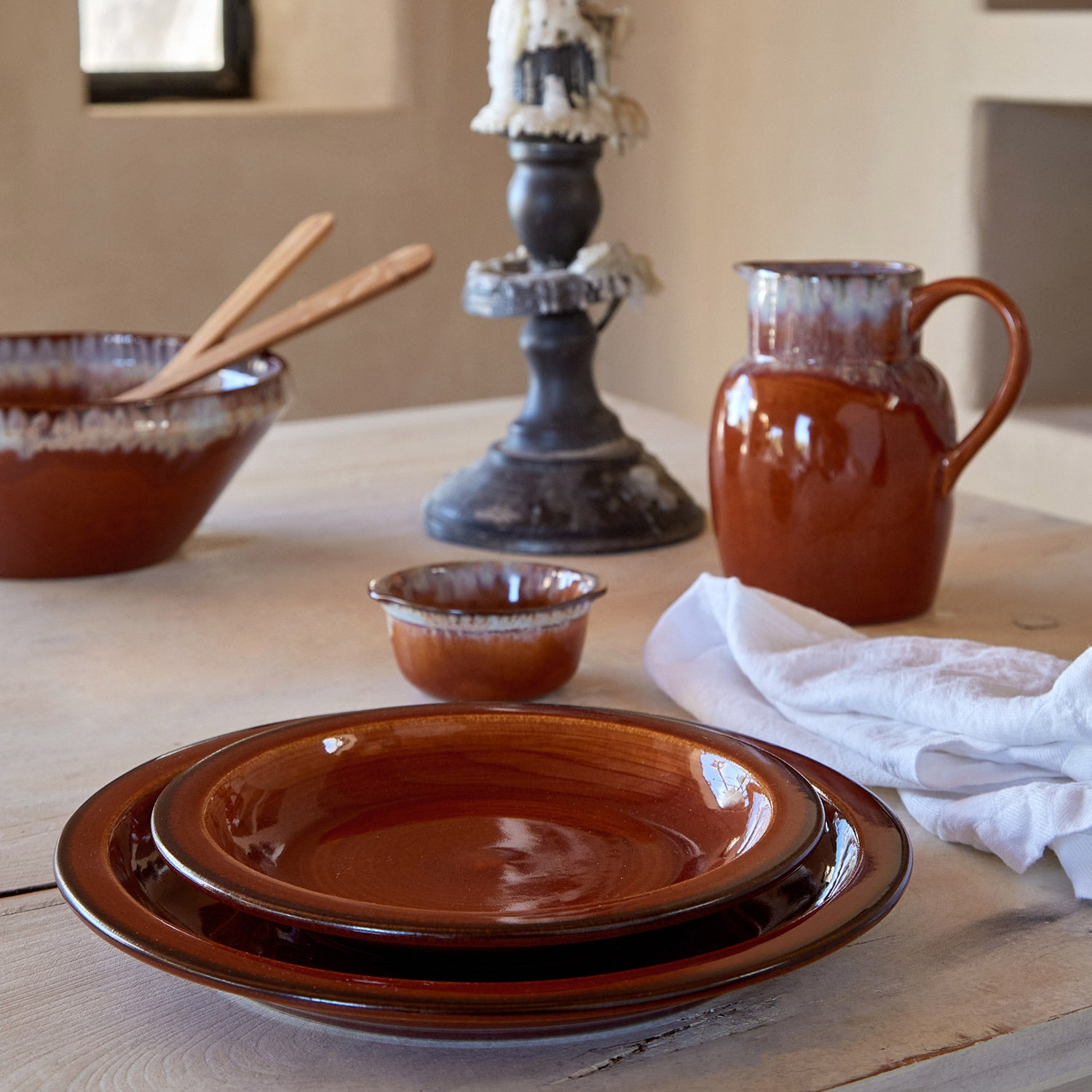 Collection of terracotta pottery arranged on wooden surface, rustic ambiance.