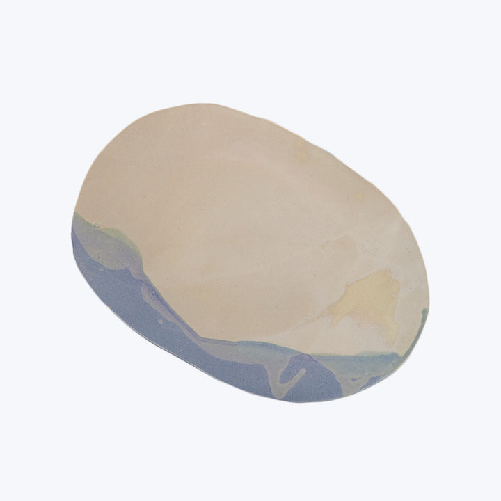 Elliptical object with marbled cream, beige, blue and green pattern.