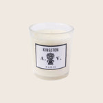 Single unlit candle in glass jar with Kingston A.V. Paris label