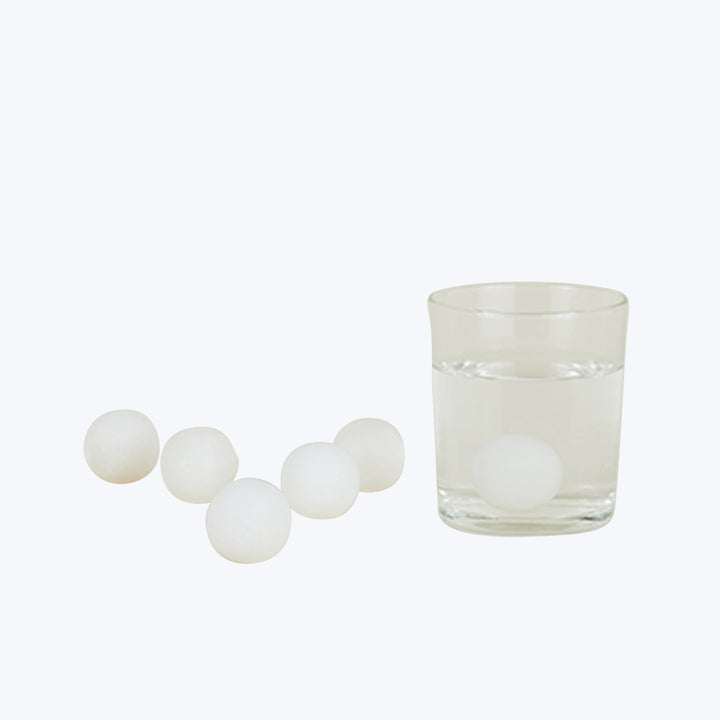 Five white spherical objects lead towards glass filled with water.