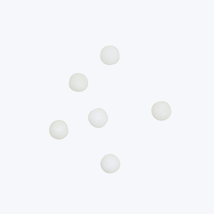 Seven white spherical objects scattered on white background, minimalist composition.