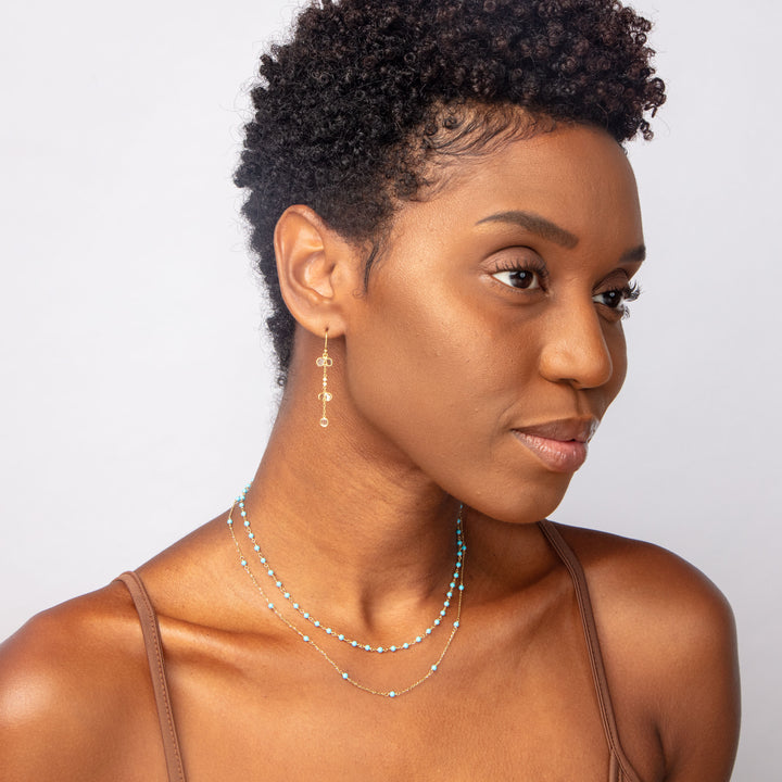 Stylish woman with dark skin, curly hair, and gold accessories.