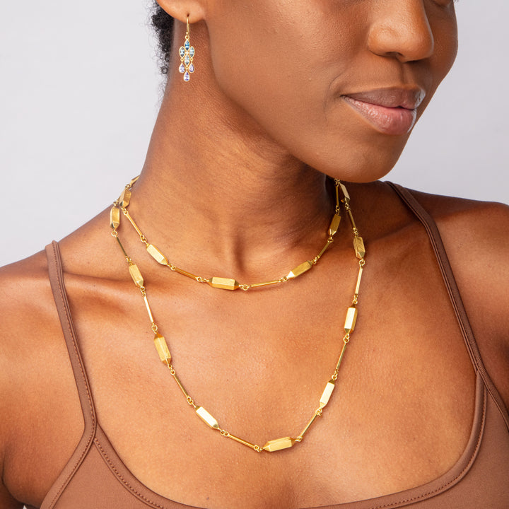 Stylish woman wearing elegant gold jewelry with blue embellishments.