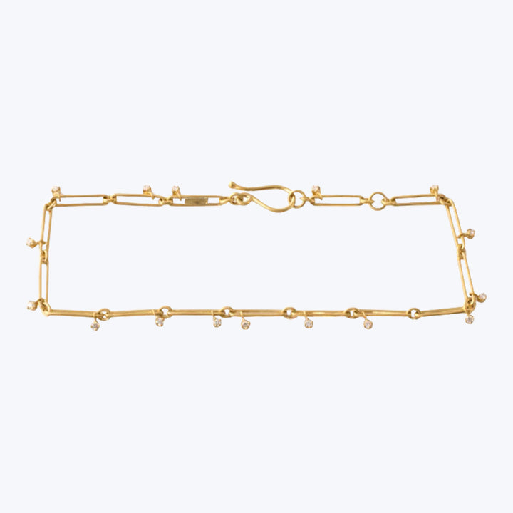 Delicate gold bracelet with intricate design featuring gemstone embellishments.