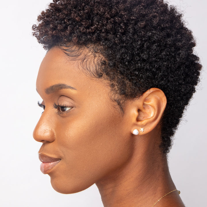 Profile of woman with short curly hair, delicate earrings, serene expression.