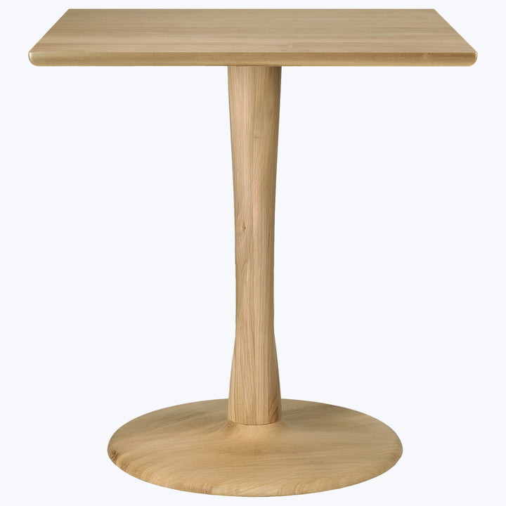 Modern, simple wooden table with tapered pedestal base, light color.