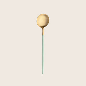 Modern gold and green spoon with sleek designer aesthetic.