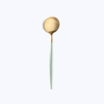 Modern gold and green spoon with sleek designer aesthetic.