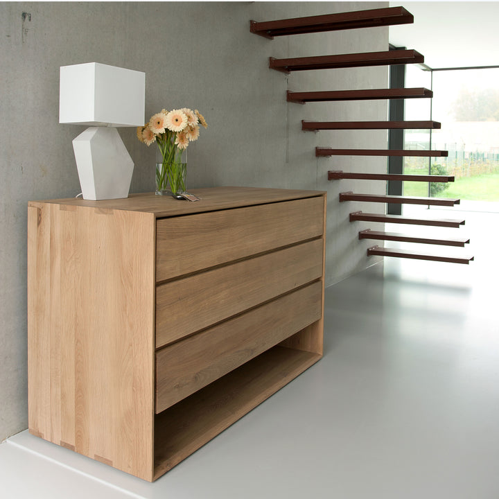 Modern minimalist interior featuring sleek sideboard, floating wooden stairs.