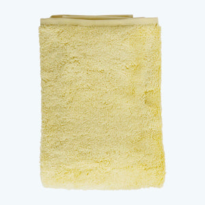 Neatly stacked pale yellow towels of different sizes on white. - hover