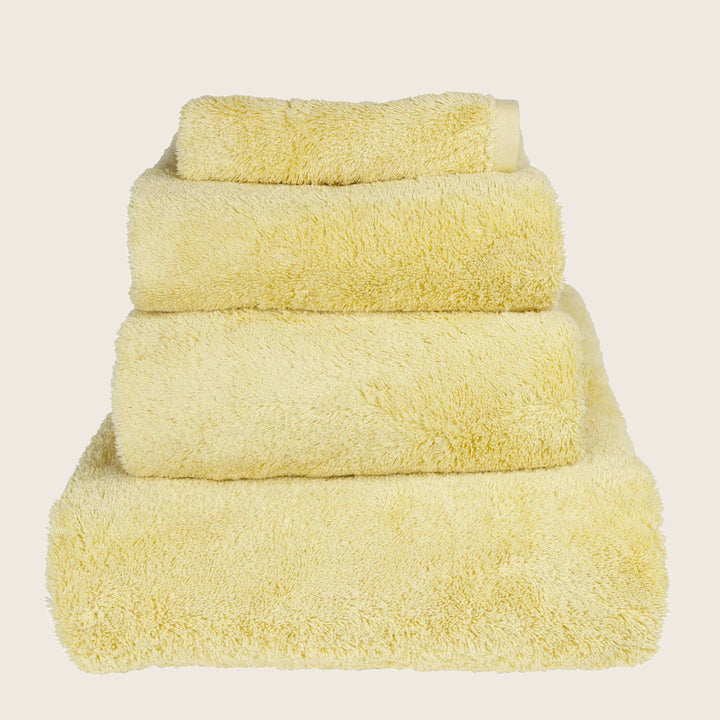 Neatly stacked pale yellow towels of different sizes on white.
