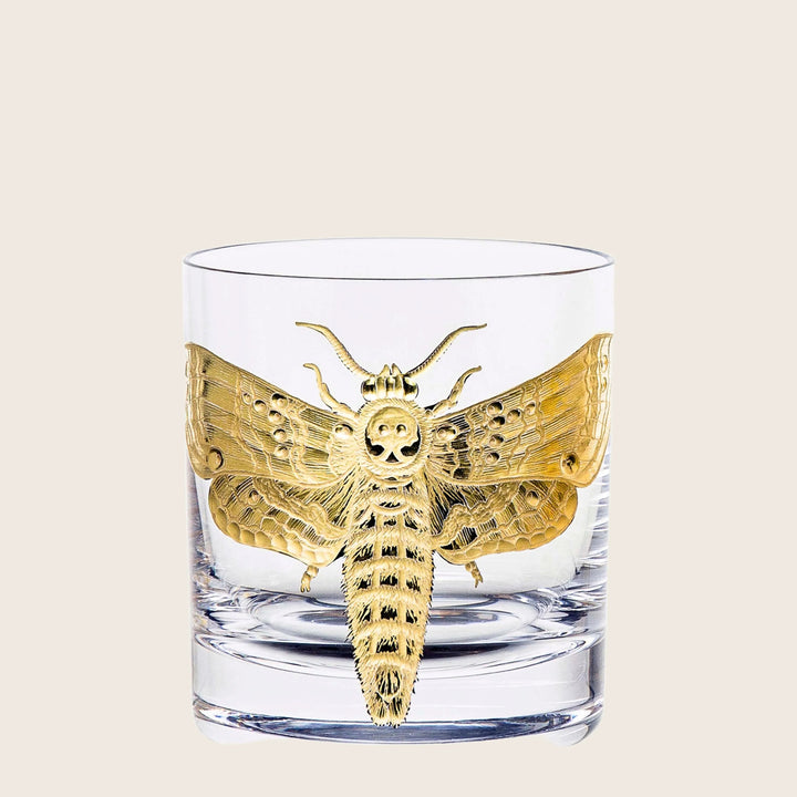 Intricate gold design on glass tumbler features moth and skull.