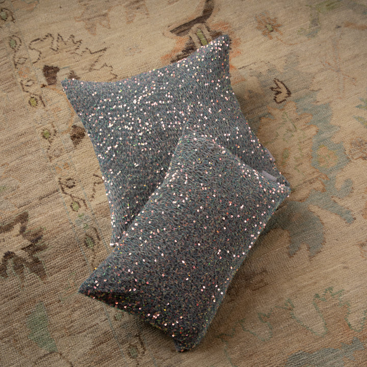 Multicolored sequined cushions on textured rug shimmer in the light.