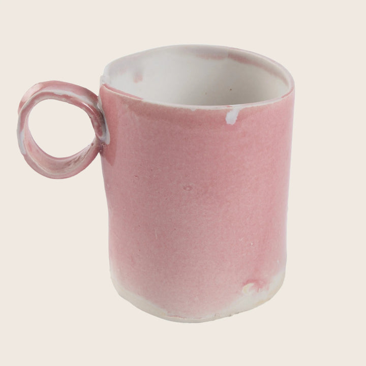 Handmade pink ceramic mug with uneven glaze finish and imperfections.
