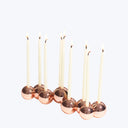 Seven sleek copper candle holders with lit creamy white tapers.