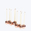 Seven sleek copper candle holders with lit creamy white tapers.