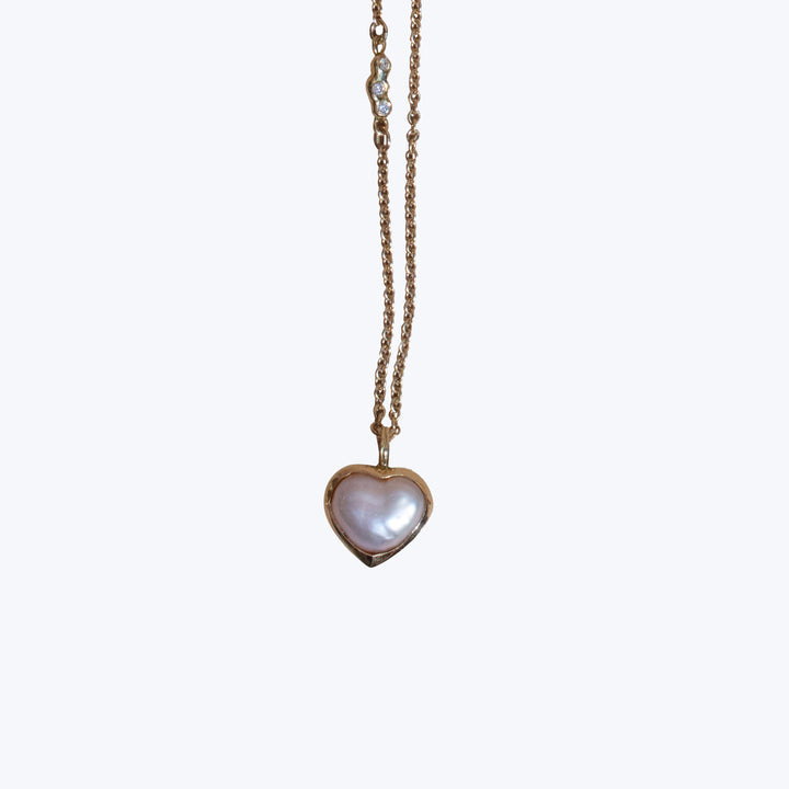 Elegant heart-shaped pendant with iridescent stone on delicate chain.