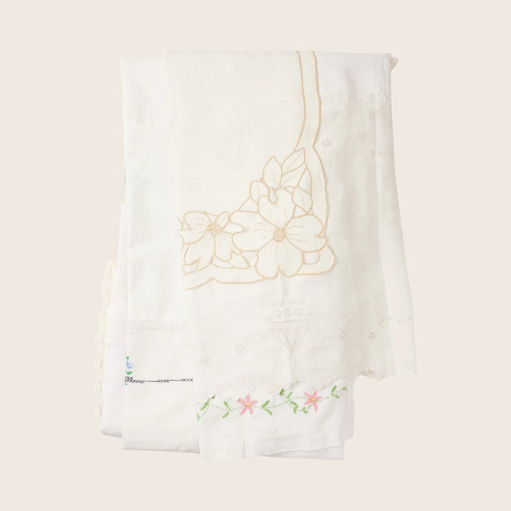White tablecloth with intricate floral embroidery and scalloped edges.