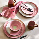 Modern pink table setting with black cutlery and elegant mugs.