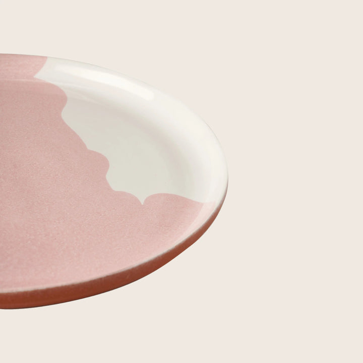 Pink ceramic plate with glazed finish on white background, modern design.