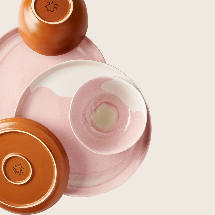 Stylish pink ceramic dishware set with terracotta accents on display.