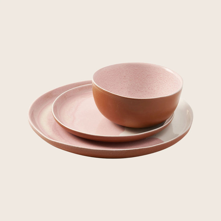 Stack of modern pink ceramic dinnerware on white background