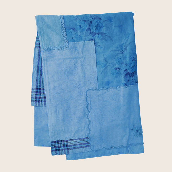 Folded blue textile with various textures, patterns and lace trim.