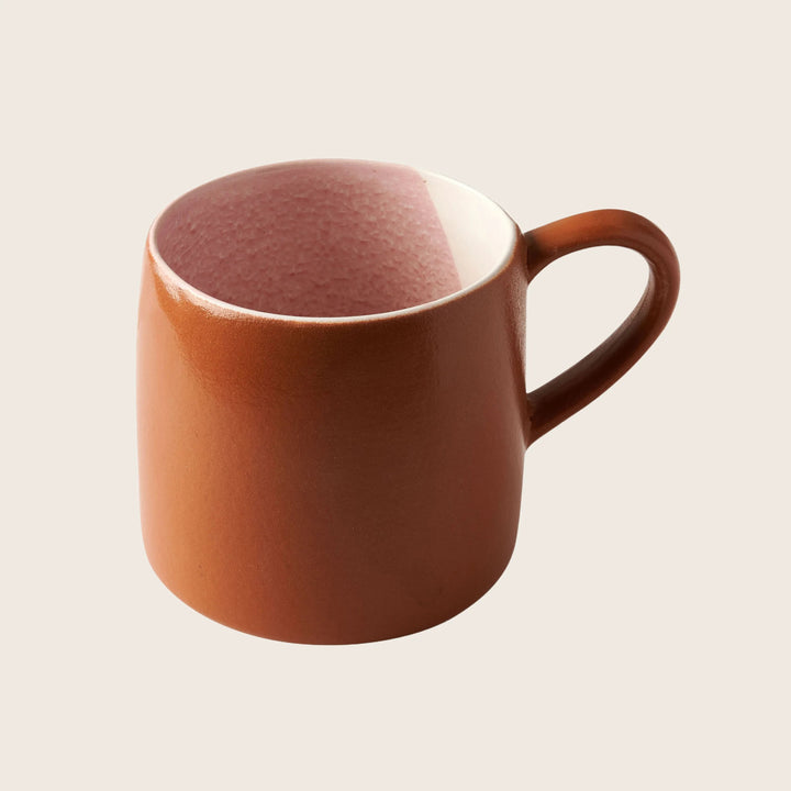 Plain brown ceramic mug with ear-shaped handle on white background.