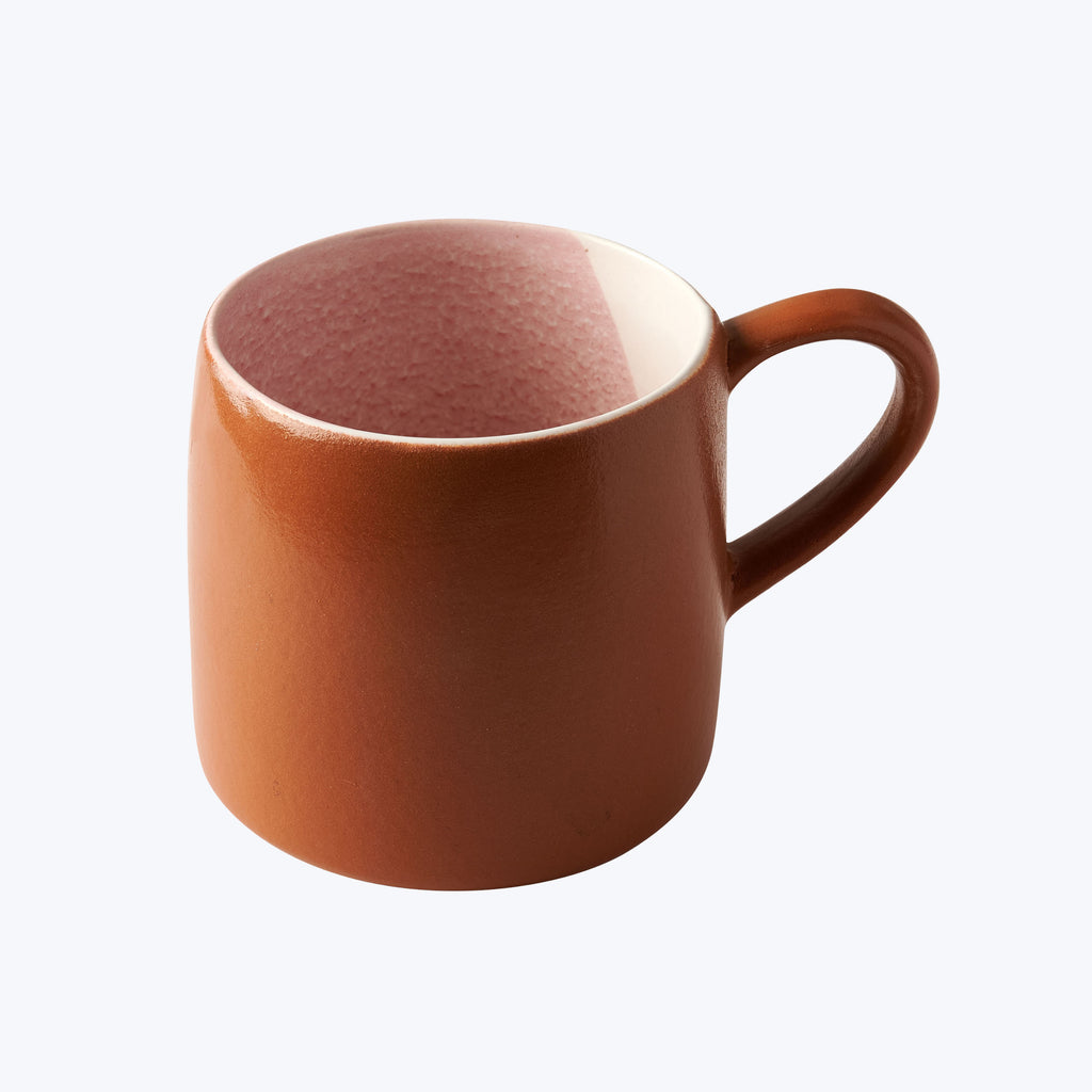 Plain brown ceramic mug with ear-shaped handle on white background.