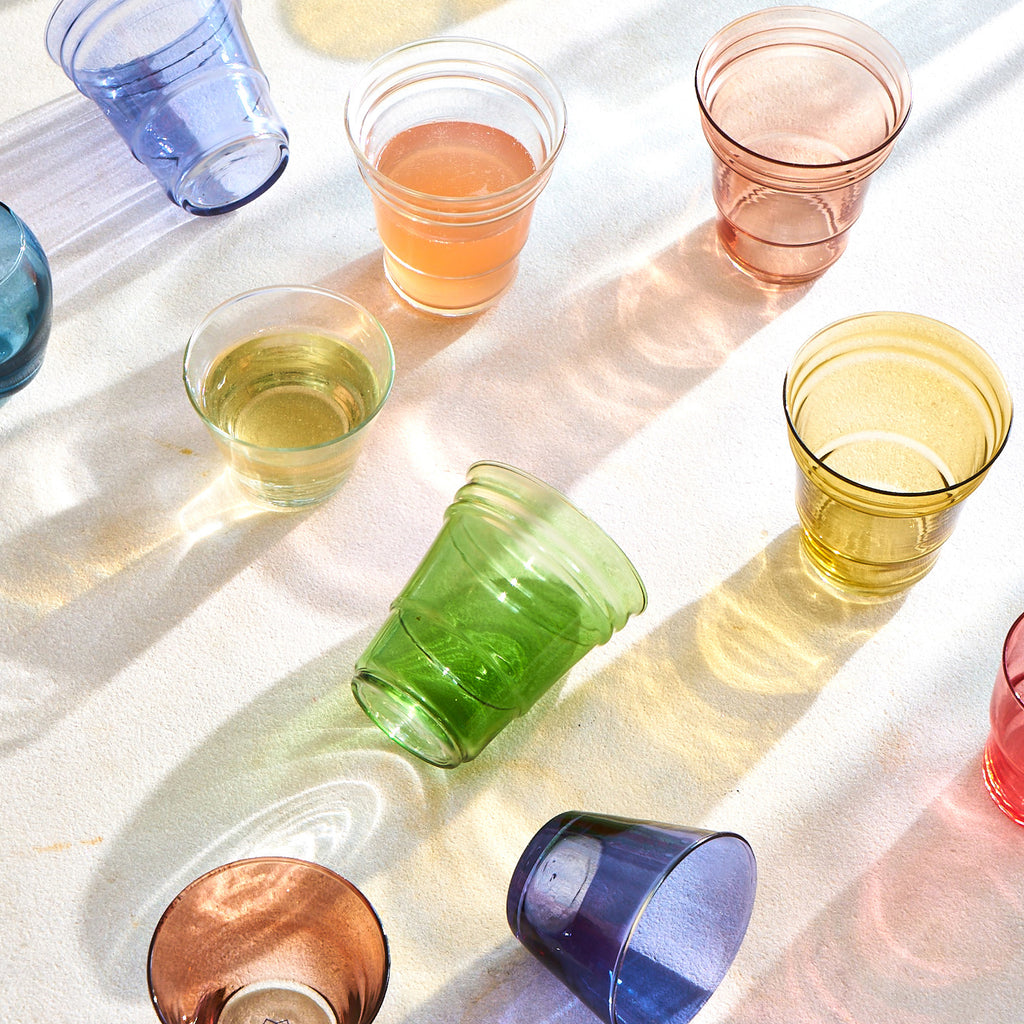 Colorful glass cups in sunlight creating shadows and reflections pattern