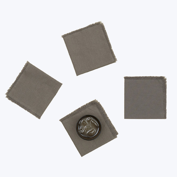 Gray fabric squares with frayed edges and circular black seal.