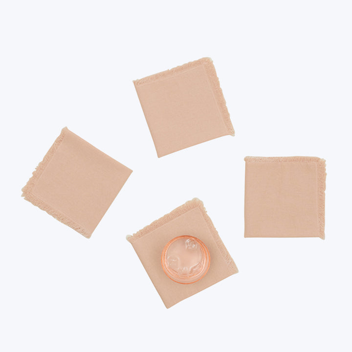 Minimalist arrangement of condoms in square wrappers on fabric squares