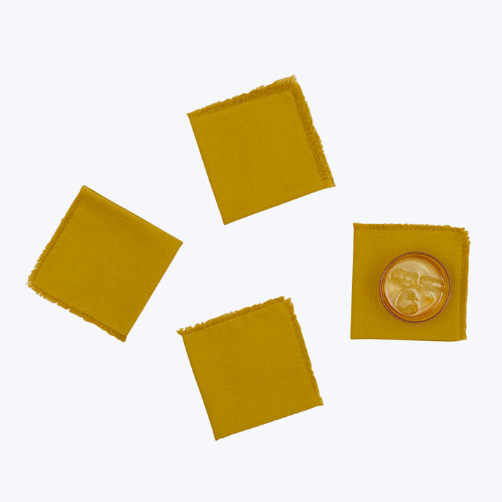 Four mustard yellow fabric squares with frayed edges and glass ornament.