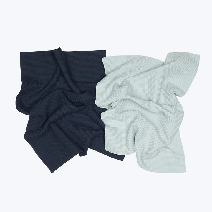 Crumpled dark blue and mint green textured fabrics overlapped together.