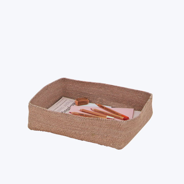 Rectangular woven beige basket holds art supplies on white background.