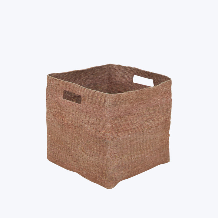 Handcrafted square jute basket with cut-out handles on white background.