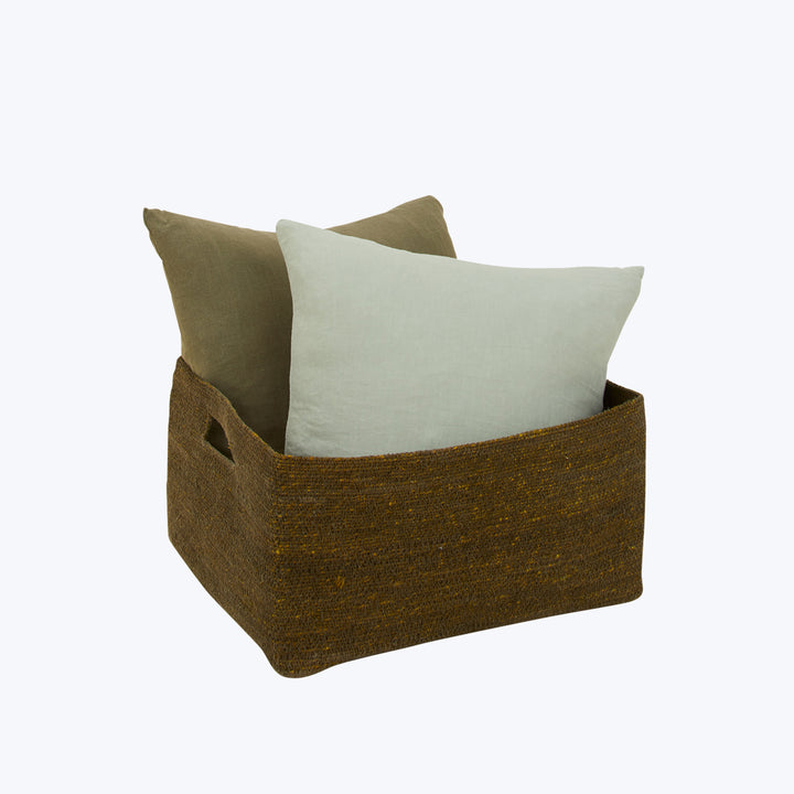 Dark brown storage basket with olive green and beige pillows.
