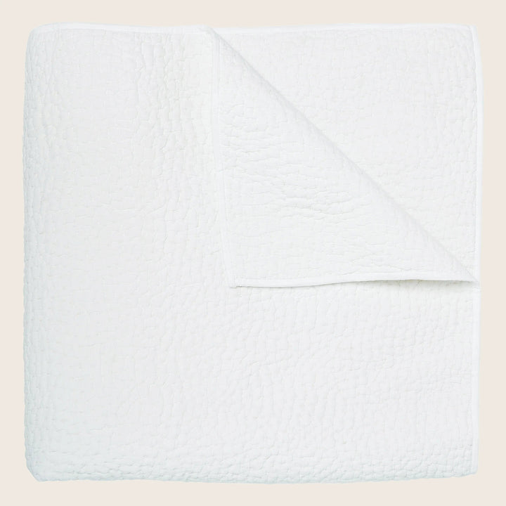 Soft, quilted white blanket folded neatly against white background.