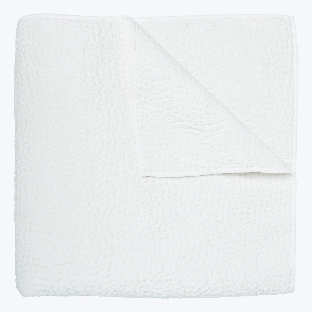 Soft, quilted white blanket folded neatly against white background.