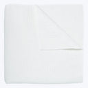 Soft, quilted white blanket folded neatly against white background.