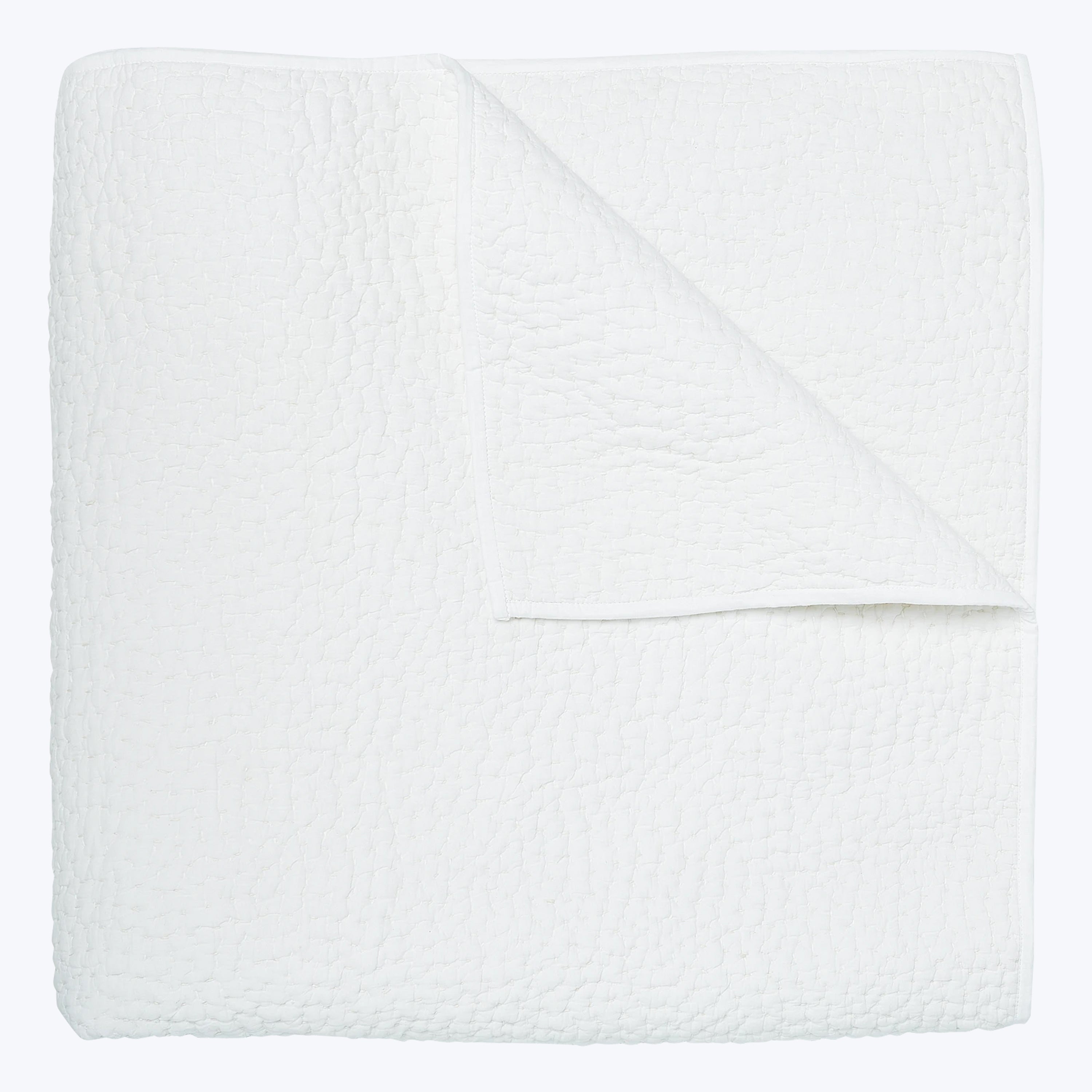 Soft, quilted white blanket folded neatly against white background.