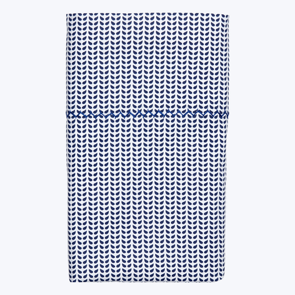 Blue teardrop patterned textile with decorative border on white background.