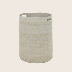 Neutral beige cylindrical fabric storage basket with cut-out handles.