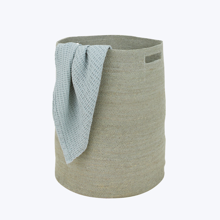 Beige fabric laundry basket with blue cloth draped over side.