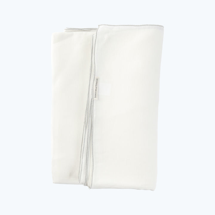 Neatly folded off-white cloth with dark trim and label edge.