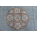 Traditional beige and white embroidered fabric with floral and geometric motifs.