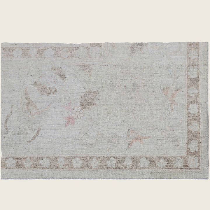 Vintage floral rug with faded pastel hues and geometric border.