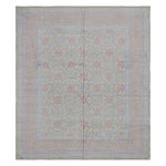 Intricate vintage rug with symmetrical floral pattern in soft colors.