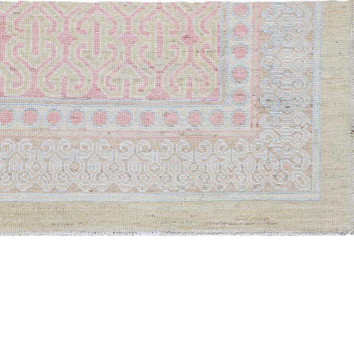 Intricately patterned textile in pastel hues shows signs of wear.