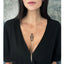 Person in black V-neck top with delicate pendant necklace.